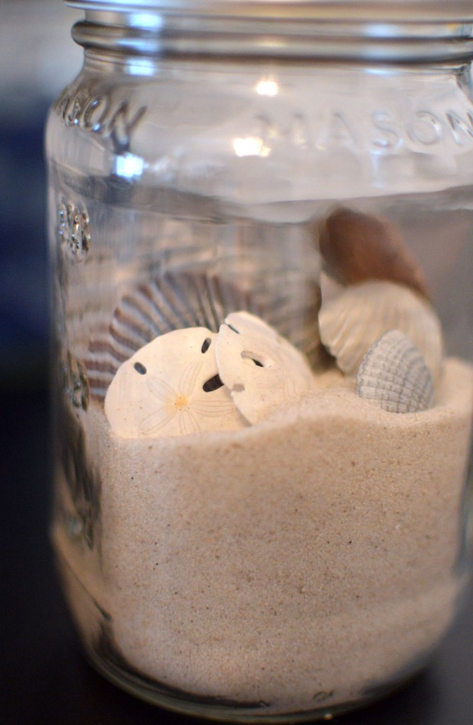 DIY laptop stand with sand and shells in a mason jar